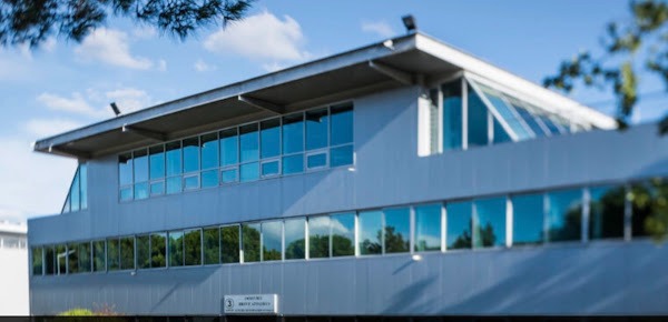 Bâtiment moderne à larges baies vitrées abritant le cabinet mage-conseil à Merignac sous un ciel bleu calme