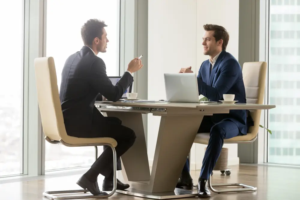 Consultation professionnelle mage-conseil à merignac entre deux hommes en costume dans un bureau moderne et lumineux
