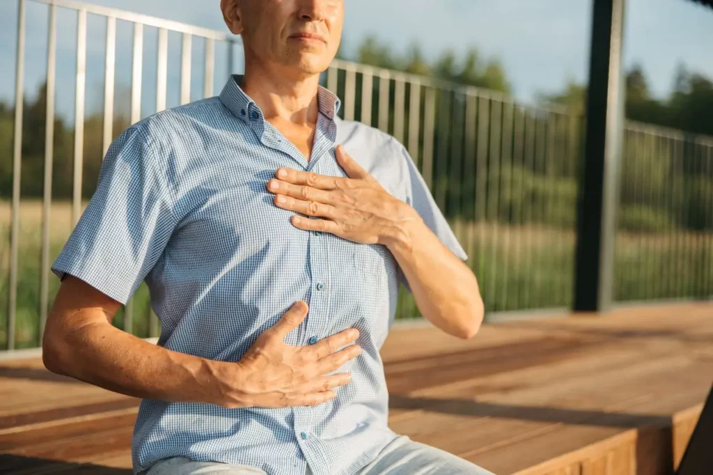 Homme en méditation guidée en plein air sur terrasse, respiration consciente avec mage-conseil à merignac